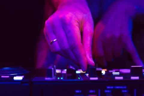 Hands of a DJ creating and regulating music on dj console mixer at club concert Stock Photos