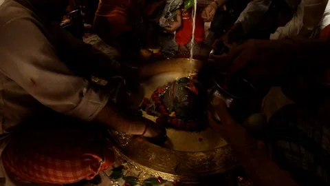 Hands do puja ritual prayer with candle to swayambhu natural lingam another peop Stock Footage 98655729