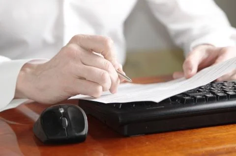 Hands with document and pen on a computer keyboard Stock Photos