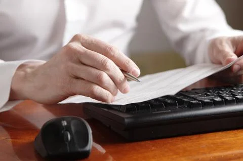 Hands with document and pen on a computer keyboard Stock Photos
