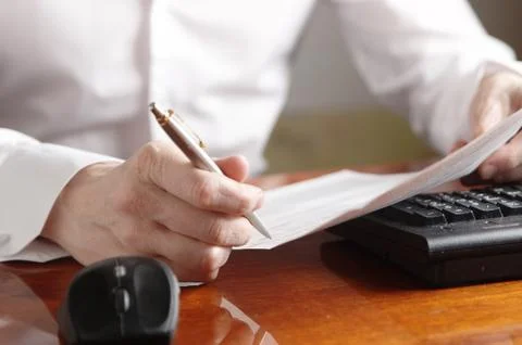 Hands with document and pen on a computer keyboard Stock Photos