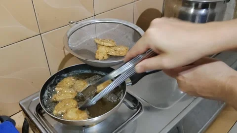Hands draining “Hekeng” on the stove using kitchen utensils Stock Footage 302375021