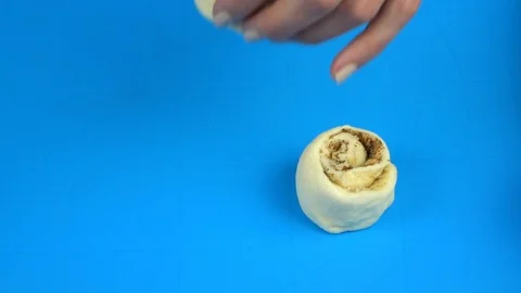 Hands drape cinnamon rolls before they come into the oven 库存影片 88451775