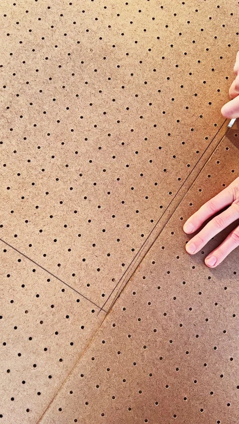 Hands draw lines on a perforated board while marking a design for a project in a Stock Footage 336488715