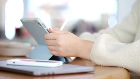 Hands draw or write on tablet, wearing white knit sweater Stock Footage 345865130