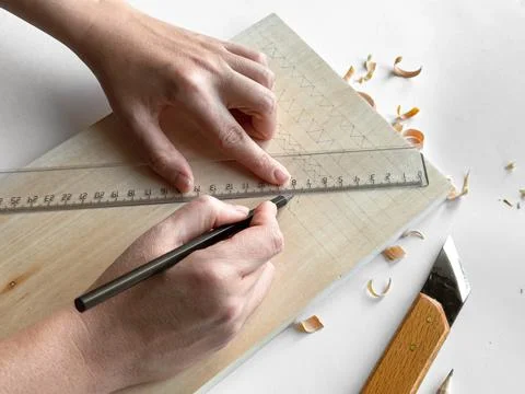 Hands drawing geometric patterns on wood with pencil and ruler Stock Photos