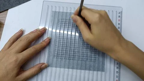 Hands drawing a grid pattern on fabric before embroidery work.  Stock Photos