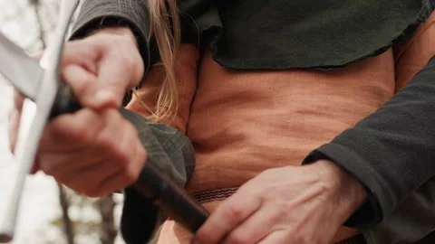 Hands drawing medieval sword with firm grip, angled blade, outdoor overcast Stock Footage 345664192