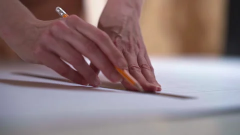 Hands drawing precise pattern lines with pencil on white drafting surface Video stock 321890276