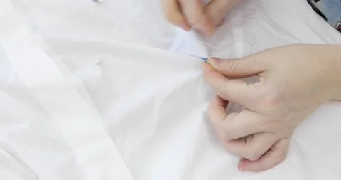 The hands of a dressmaker sewing sequins to white cotton textile. Stock Footage 157324460