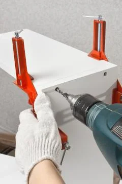 Hands drilling a hole during assembling of chipboard furniture Stock Photos