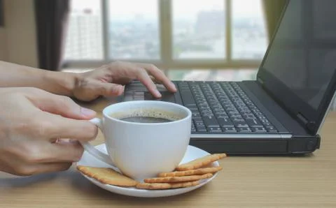Hands drinking coffee and using laptop and Blurred bedroom window background Stock Photos