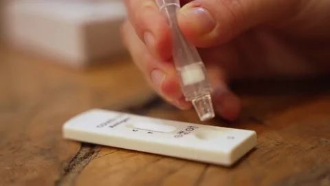 Hands drips buffer fluid into Covid-19 antigen home testing device kit Stock Footage 169387502