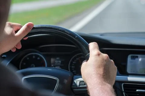 Hands of a driver gripping the steering wheel of a car on a sunny day Stock Photos