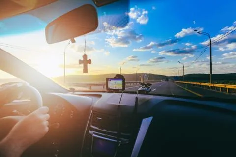 Hands of driver on steering wheel of car with orthodox cross and car navigator Stock Photos