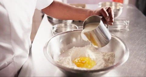 Hands, eggs or pouring milk in flour on table, chef or process of dough wheat on Video stock 263413546
