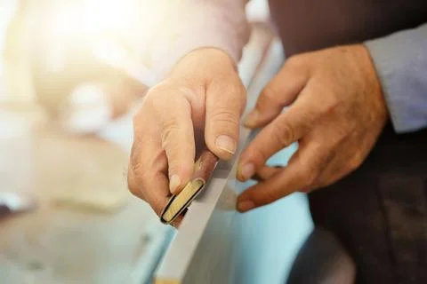 The hands of an elderly carpenter and a tool while working in close-up. Stock Photos