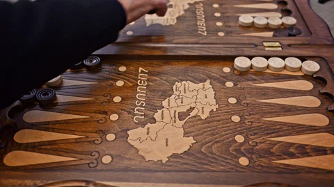 Hands of an elderly man and elderly woman playing backgammon, man rolling dice Stockbeeldmateriaal 328607876