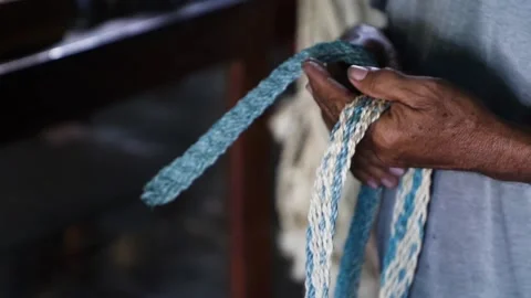 Hands of an elderly man with dark skin, stretching some handmade belts Stock Footage 144074058