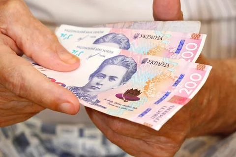 In the hands of an elderly man there are Ukrainian hryvnia bills. Stock Photos