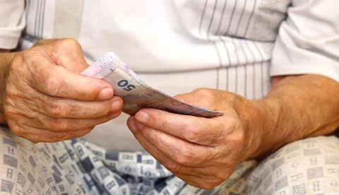 In the hands of an elderly man there are Ukrainian hryvnia bills. Stock Photos