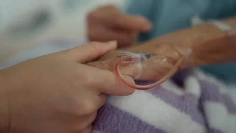 Hands of elderly patient with IV drip with hand of visiting comfort and support. Stock Footage 326084940