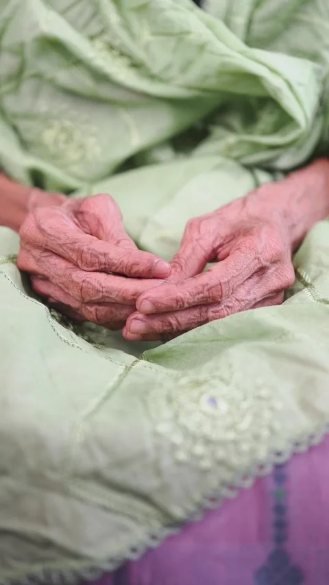 Hands of an elderly person resting on a green shawl Video stock 338152010