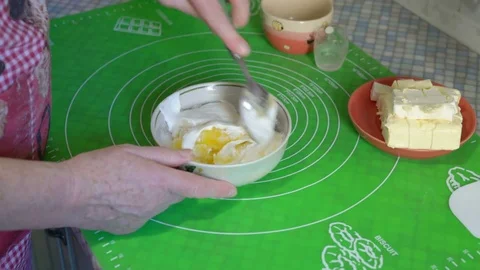 Hands of an Elderly Woman at the Help of a Spoon Mix in a Plate Ingredients for Stock Footage 85392965