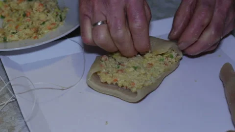 Hands of elderly woman preparing stuffed pork rind. Stock-Footage 152879200