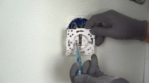 Hands of electrician check current in socket using indicator screwdriver. Outlet Stock Footage 277953748