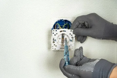 Hands of electrician check current in socket using indicator screwdriver. O.. Stock Photos