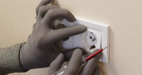 Hands of electrician in gloves repair white socket in room Stock Footage 201379341
