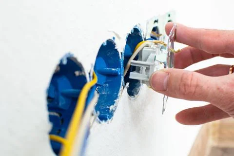 Hands of electrician installing electrical socket with new home Foto stock