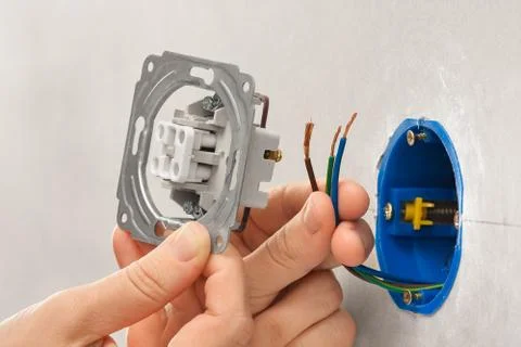 Hands of electrician installing light switch in plasterboard wall Stock Photos