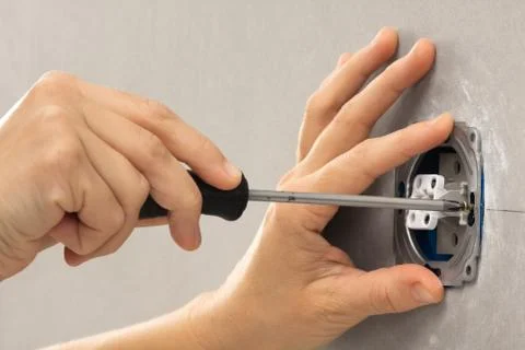 Hands of electrician installing light switch with screwdriver Stock Photos