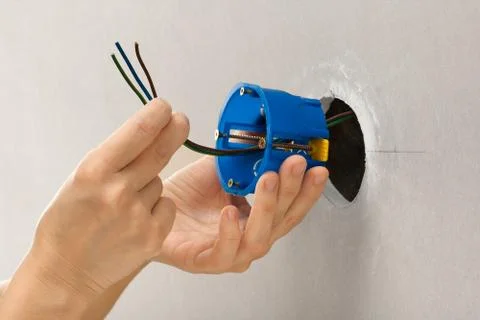 Hands of electrician installing plastic outlet box Stock Photos