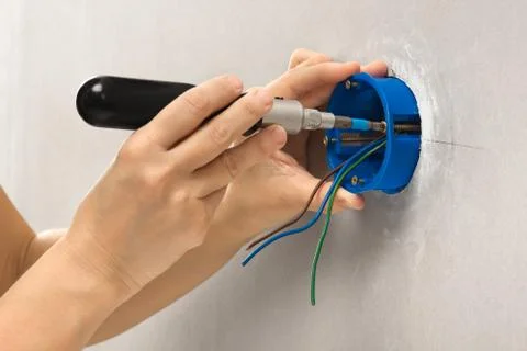 Hands of electrician with screwdriver installing plastic outlet box Stock Photos