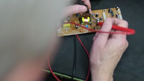 Hands of an electrician using a multimeter to test a circuit board, checking Stock Footage 302352649