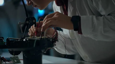 Hands-on electronics work in a dimly lit workshop focused on robotics assemb Stock Footage 323807191