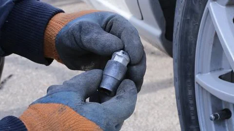 Hands with emblems holding a car bolt at the wheel Stock Photos