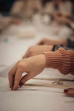 Hands engaged in creating delicate macrame on a bright white table, represe.. Stock Photos