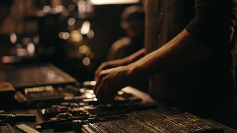 Hands engaged in newspaper printing press work in a dark atmospheric setting Stock Footage 320024579