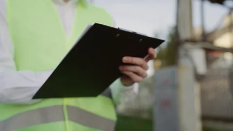 Hands of the Engineer in Vests Taking Notes Outside near the Power Lines. Stock Footage 242589012