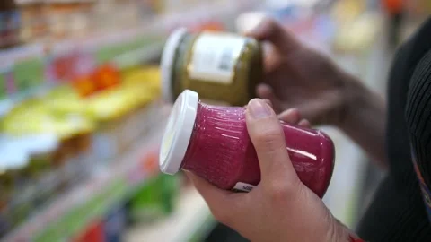 Hands examine and compare labels on jars of dressings or sauces in a supermarket 스톡 동영상 316038806