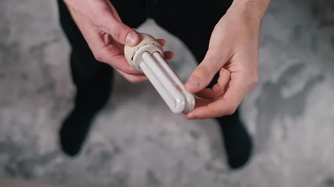 Hands Examining Energy-Saving CFL Bulb - Overhead View Stock Footage 307227803