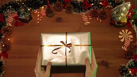 Hands exchanging a beautifully wrapped silver gift box in a festive holiday.. Stock Footage 304515229