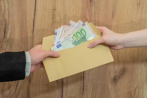 Hands exchanging an envelope filled with a stack of euro banknotes. Cash Stock Photos