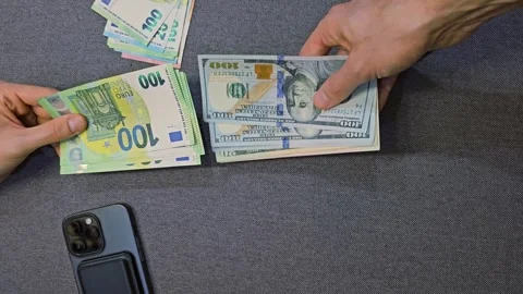 Hands exchanging euro and US dollar banknotes on gray surface Stock Footage 310851589