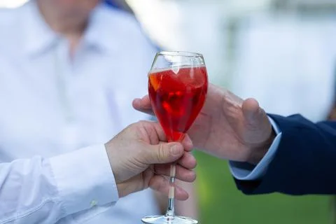 Hands exchanging a refreshing aperol spritz cocktail outdoors Stock-Fotos