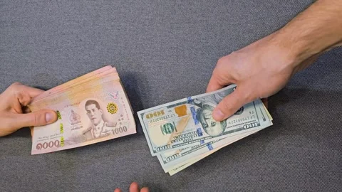 Hands exchanging US dollar and Thai baht banknotes. Currency exchange Stock Footage 310844834